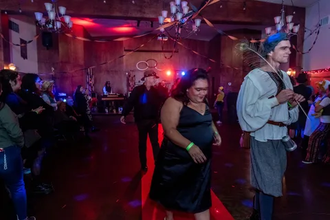 A couple in costume, one in medieval dress, stand together on the ballroom floor.