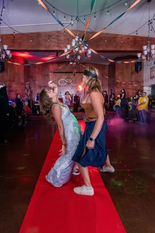 Two women in costume dance under the colored lights.