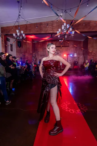 A woman in a dark red dress strikes a pose on the ballroom's red carpet.