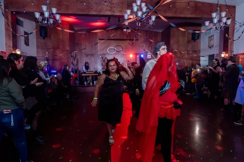 Two women in costume pose together on the dance floor.