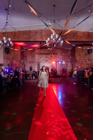 A woman in a white lace gown poses with a hand on her hip near the ballroom entrance.
