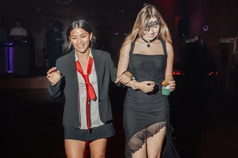 Two women, one with skeleton face paint, walk together on the runway.