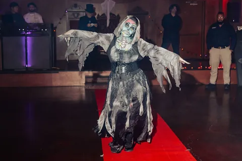 Two zombie-costumed guests reach outward together in a dramatic pose on the runway.