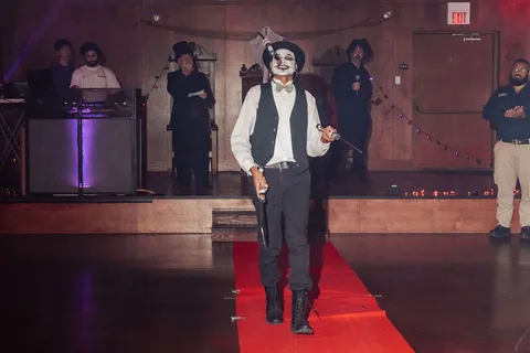 A man with joker-style face paint stands at the end of the runway.