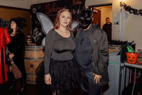A woman with fairy wings poses next to a man in a masked costume.