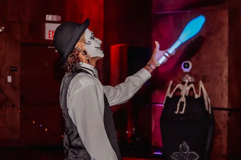 A performer juggles glow sticks mid-movement on the small stage.
