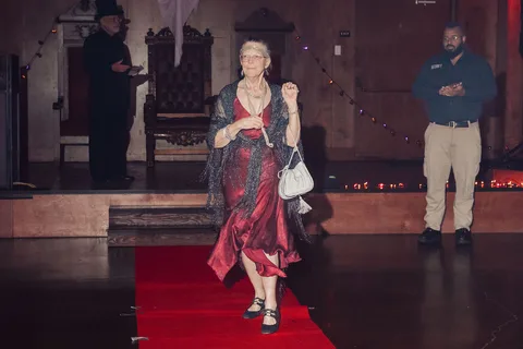 The same woman in a red dress walks the runway from another angle.
