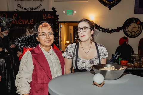 A man and woman in costume stand together near a serving table.