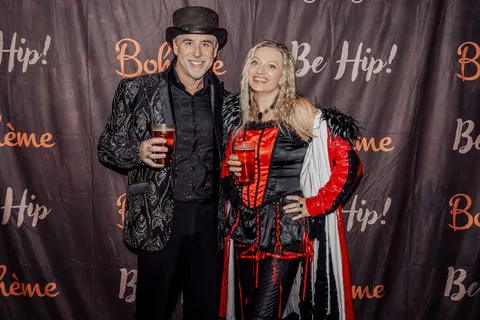 A costumed trio poses together in front of the Boheme backdrop.