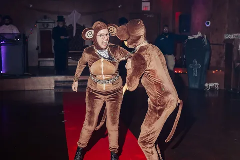 Two guests in brown monkey costumes dance together on the runway.