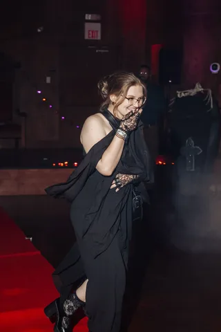 A woman in a black dress laughs candidly near the runway.