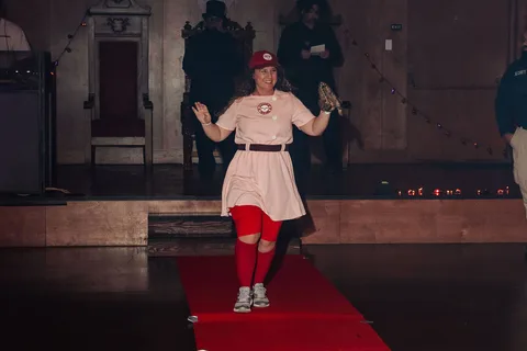 The softball costumed woman poses from another angle on the runway.