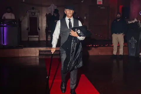 A man in a vest walks alone with a cane, seen at a distance on the runway.