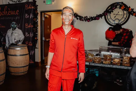 A man in a bright orange tracksuit costume poses solo inside the venue.