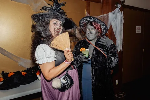 Two women in elaborate zombie makeup and Victorian costumes pose together.