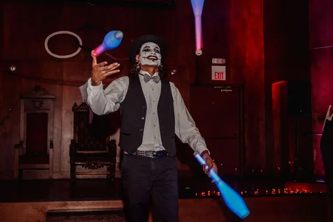 A performer juggles glow sticks in the dim lighting.