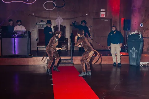 Two guests in monkey costumes dance mid-motion on the runway.