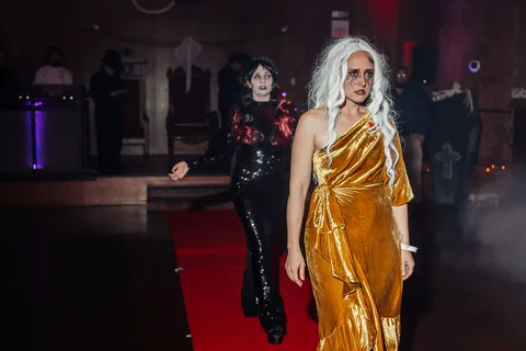 The two gowned women walk mid-stride, dynamic on the runway.