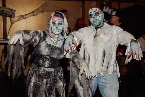 Two guests in full zombie costume reach toward the camera in a dramatic pose.