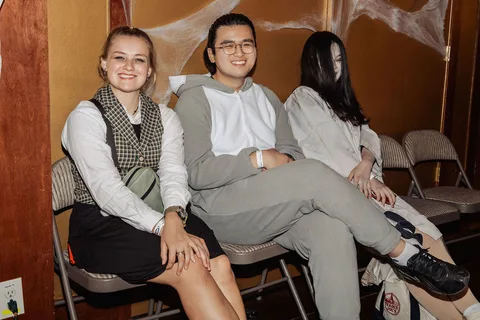 Three young guests sit together relaxing at the party.