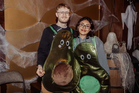 A couple dressed as avocados smile together at the party.
