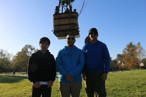 Three young men stand together on the grass after the flight.