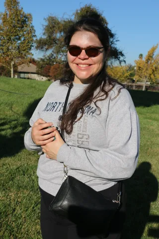 A teenager grins warmly in the morning sun on the grass.