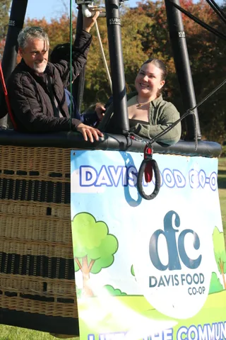 Another view of the group in dark jackets in the balloon basket, faces not visible.