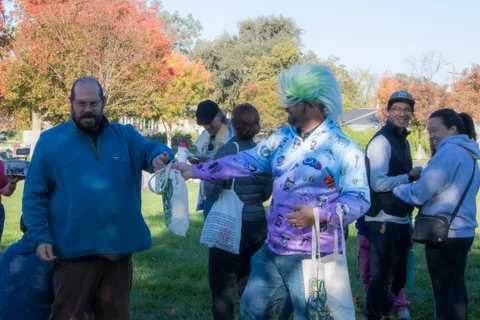 A man in a blue jacket exchanges an item with costumed volunteers.