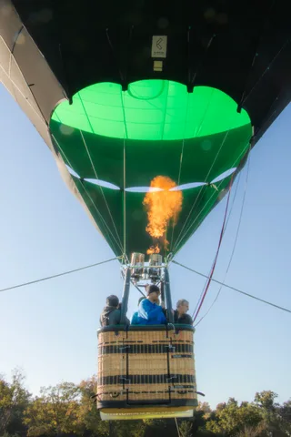 An orange flame plume ignites from the burner with a rider small at the frame's edge.