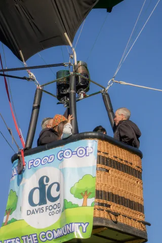 A hot air balloon basket with a Davis Food Co-op banner fills the frame, no riders visible.