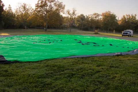 The balloon's green envelope lies flat and deflated on the grass.