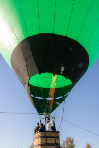 Flame glow lights the underside of the green balloon envelope in an abstract close view.
