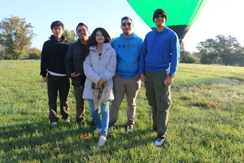 The same group of friends poses again with the balloon behind them.