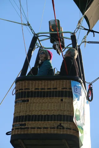 Riders are partly visible in the basket against the sky.