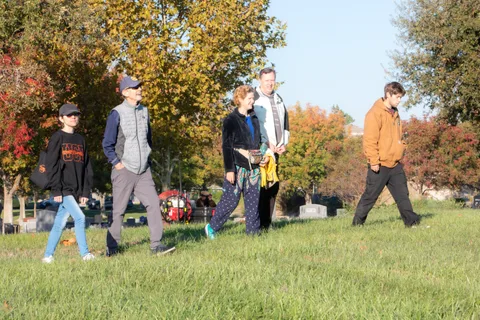 A group of five or six walks together across the grass in warm fall light.
