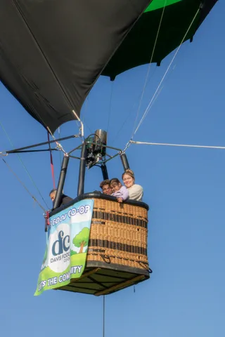 Faces peer over the basket rim beneath the Davis Food Co-op banner against open sky.