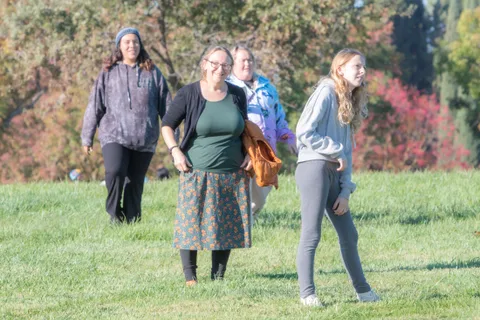 Three guests walk across the grass field at mid distance.