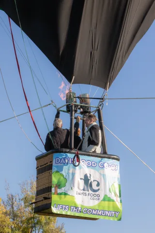 Riders are barely visible over the rim as the basket rises against open sky.