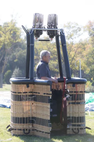 A man operates the balloon burner controls in the early morning light.