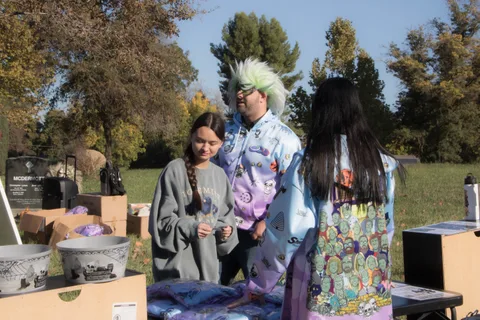 Two costumed guests stand at a booth table, seen mostly from behind.