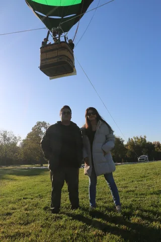 A couple stands together watching the balloon overhead.