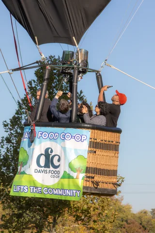 A man in a red cap throws his arm up excitedly as the basket rises.