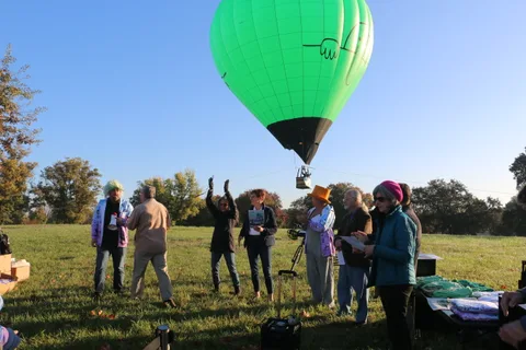 Onlookers raise their arms as the balloon looms overhead in the morning light.