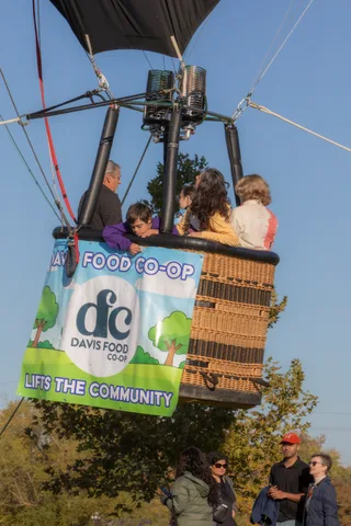 Three riders in mixed colors stand together beneath the Davis Food Co-op banner.