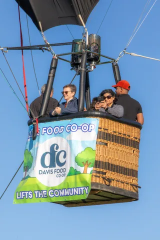 A man in a red cap and two women in sunglasses smile together in the basket.