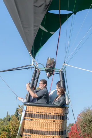 A man takes a photo with his phone while a woman stands beside him in the basket.