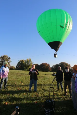 The balloon envelope and basket rise at a dramatic angle against clear sky.