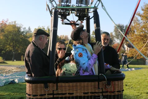 A rider adjusts a costume hood while others look on in the basket.