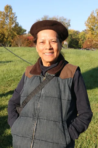 A woman in a brown beret smiles warmly in the morning sun.